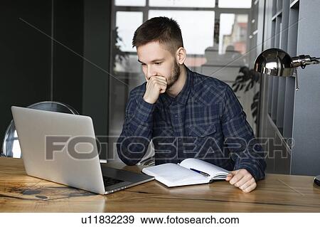 Stock Photo - Young businessman looking at laptop. Fotosearch
