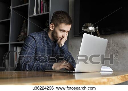 Stock Photograph - Young businessman looking at laptop. Fotosearch