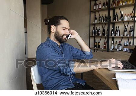 Young businessman on phone by laptop View Large Photo Image Picture - Young businessman on phone by laptop. Fotosearch