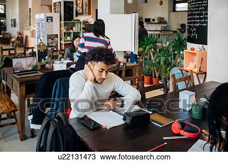 Stock Image - Young businessman remote working at cafe table. Fotosearch
