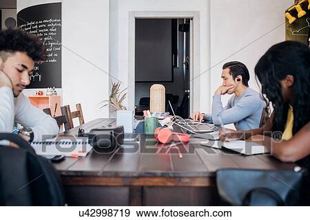 Stock Photo - Young businessmen and woman remote working at cafe table. Fotosearch