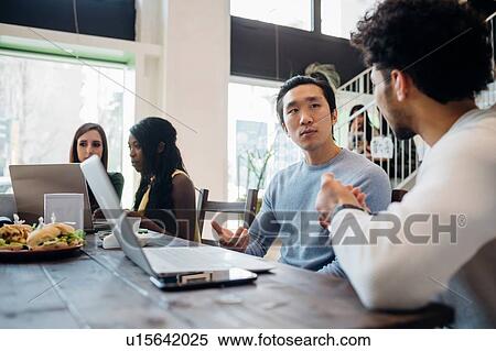 Young businessmen having discussion at cafe table View Large Photo Image Stock Photography - Young businessmen having discussion at cafe table. Fotosearch