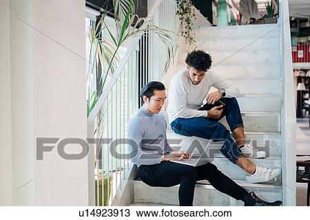 Young businessmen sitting on stairway using laptop View Large Photo Image Stock Image - Young businessmen sitting on stairway using laptop. Fotosearch
