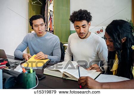 Stock Photo - Young businesswoman and men having informal research meeting at table. Fotosearch