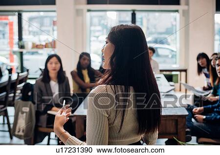 Stock Image - Young businesswoman doing presentation for colleagues. Fotosearch