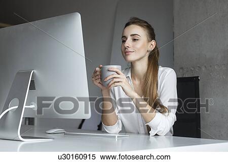 Young businesswoman holding coffee cup at desk View Large Photo Image Stock Photography - Young businesswoman holding coffee cup at desk. Fotosearch