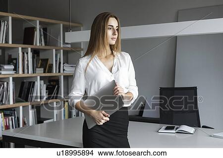 Young businesswoman holding laptop in office View Large Photo Image Picture - Young businesswoman holding laptop in office. Fotosearch