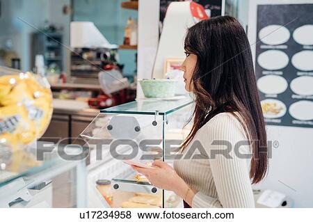 Young businesswoman holding smartphone at cafe counter View Large Photo Image Stock Photo - Young businesswoman holding smartphone at cafe counter. Fotosearch