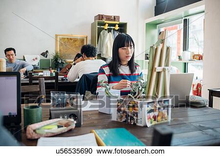 Stock Image - Young businesswoman looking at laptop in cafe. Fotosearch