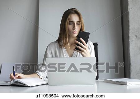 Young businesswoman looking at smartphone View Large Photo Image Picture - Young businesswoman looking at smartphone. Fotosearch