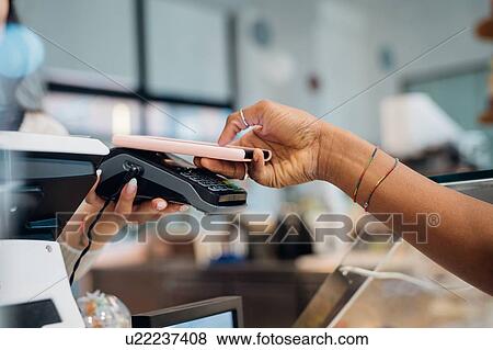 Young businesswoman making smartphone payment at cafe counter, cropped View Large Photo Image Stock Photo - Young businesswoman making smartphone payment at cafe counter, cropped. Fotosearch