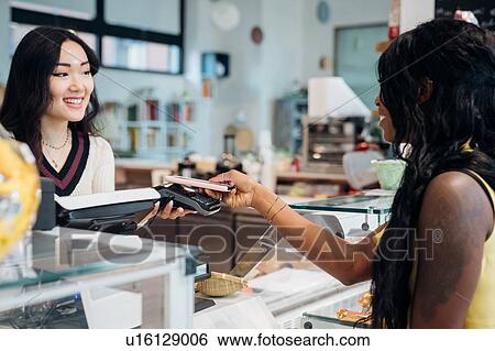 Young businesswoman making smartphone payment at cafe counter View Large Photo Image Stock Photograph - Young businesswoman making smartphone payment at cafe counter. Fotosearch