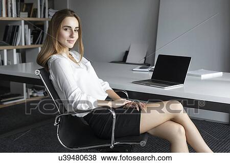 Stock Photo - Young businesswoman sitting at desk. Fotosearch