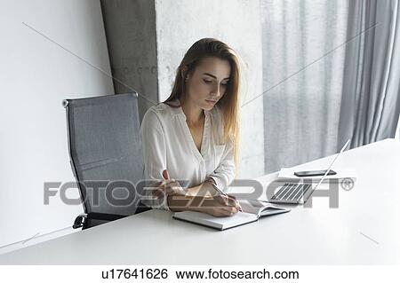 Young businesswoman taking notes at desk View Large Photo Image Stock Photograph - Young businesswoman taking notes at desk. Fotosearch