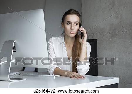 Young businesswoman taking phone call at desk View Large Photo Image Stock Image - Young businesswoman taking phone call at desk. Fotosearch