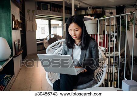 Young businesswoman using laptop in bookshop View Large Photo Image Stock Image - Young businesswoman using laptop in bookshop. Fotosearch