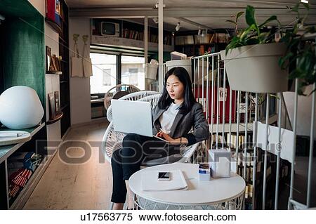 Young businesswoman using laptop in bookshop View Large Photo Image Stock Photography - Young businesswoman using laptop in bookshop. Fotosearch