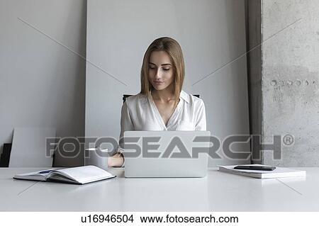 Picture - Young businesswoman working at desk. Fotosearch