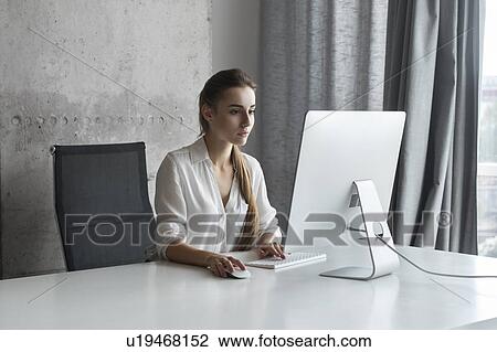 Stock Image - Young businesswoman working on desktop computer. Fotosearch