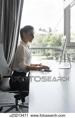 Young businesswoman working on desktop computer View Large Photo Image Stock Image - Young businesswoman working on desktop computer. Fotosearch