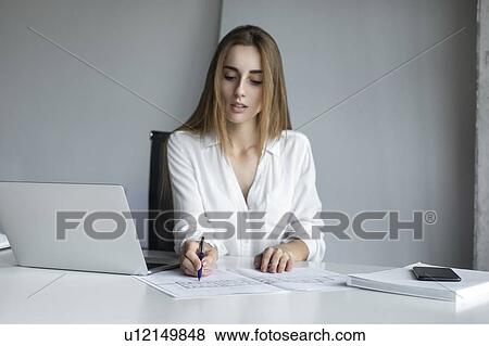 Stock Photo - Young businesswoman working on blueprints. Fotosearch