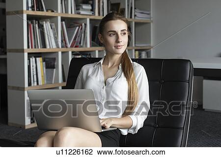 Young businesswoman working with laptop on sofa View Large Photo Image Stock Image - Young businesswoman working with laptop on sofa. Fotosearch