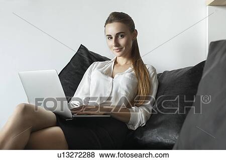 Young businesswoman working with laptop on sofa View Large Photo Image Stock Photo - Young businesswoman working with laptop on sofa. Fotosearch