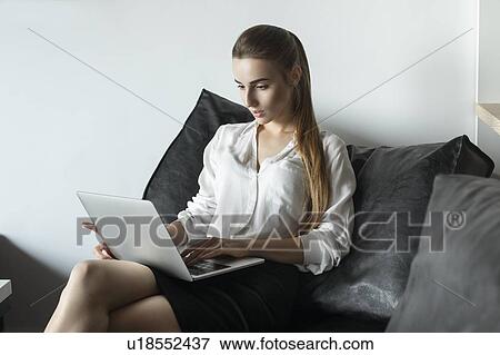 Young businesswoman working with laptop on sofa View Large Photo Image Stock Photo - Young businesswoman working with laptop on sofa. Fotosearch