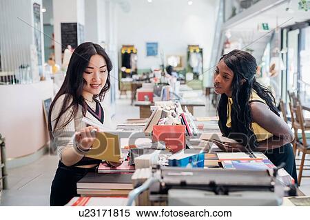 Stock Photography - Young businesswomen browsing book in bookshop. Fotosearch