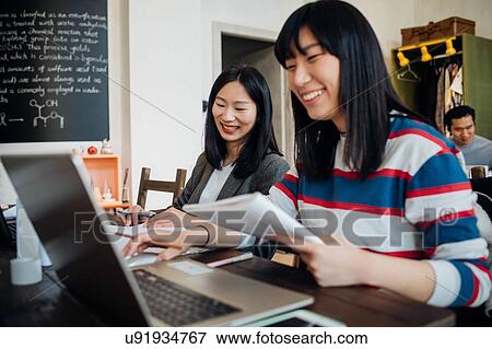 Young businesswomen working on laptop at table View Large Photo Image Stock Photo - Young businesswomen working on laptop at table. Fotosearch
