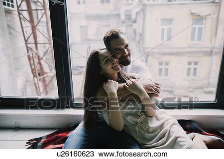 Young couple embracing by apartment window View Large Photo Image Stock Image - Young couple embracing by apartment window. Fotosearch