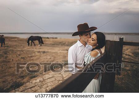 Young couple embracing in field by horses View Large Photo Image Stock Image - Young couple embracing in field by horses. Fotosearch