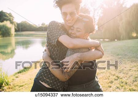 Stock Photo - Young couple hugging by lake. Fotosearch