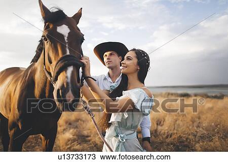Stock Image - Young couple with horse in field. Fotosearch