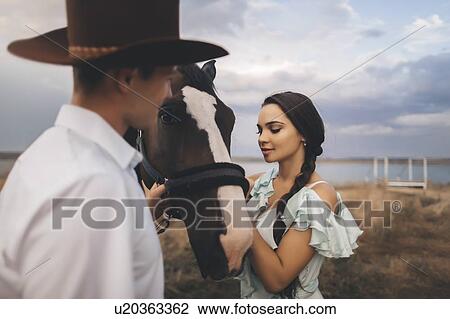 Stock Image - Young couple with horse in field. Fotosearch