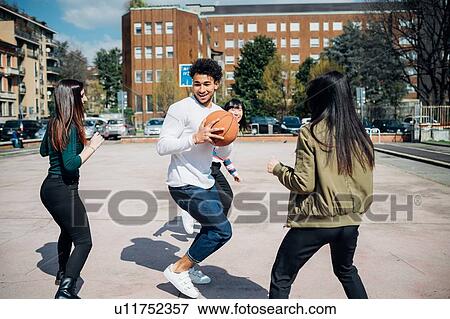 Young female and male adult friends playing basketball on city court View Large Photo Image Stock Photo - Young female and male adult friends playing basketball on city court. Fotosearch
