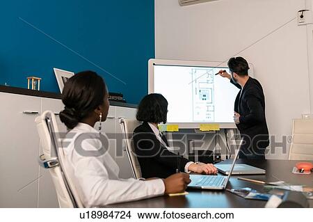 Young female and male business creative team at conference table presentation looking at interactive screen View Large Photo Image Picture - Young female and male business creative team at conference table presentation looking at interactive screen. Fotosearch