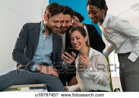 Young female and male business creative team looking at smartphone in office View Large Photo Image Stock Photo - Young female and male business creative team looking at smartphone in office. Fotosearch