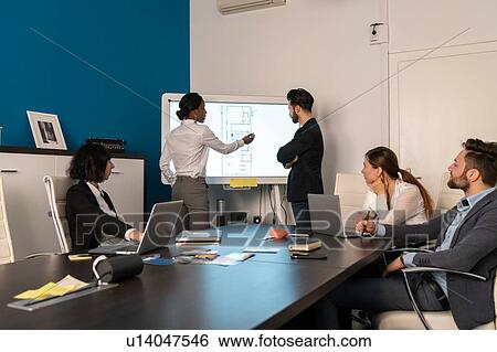 Young female and male business creative team at conference table presentation looking at interactive screen View Large Photo Image Stock Photograph - Young female and male business creative team at conference table presentation looking at interactive screen. Fotosearch