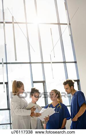 Stock Photo - Young female and male junior doctors looking at medical records in hospital. Fotosearch