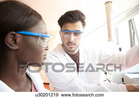 Stock Photo - Young female and male scientists having discussion in laboratory. Fotosearch
