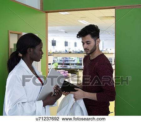Young female and male scientists in laboratory doorway View Large Photo Image Stock Image - Young female and male scientists in laboratory doorway. Fotosearch