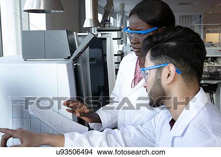 Picture - Young female and male scientists discussing paperwork in laboratory. Fotosearch
