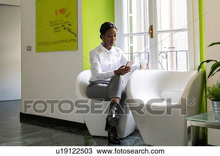 Young female business creative looking at smartphone in office armchair View Large Photo Image Stock Image - Young female business creative looking at smartphone in office armchair. Fotosearch