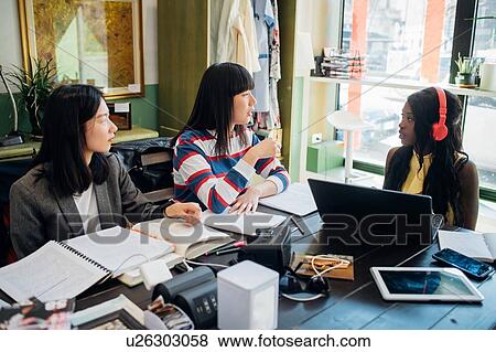 Stock Photo - Young female business team meeting at cafe table. Fotosearch