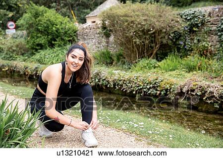Young female runner tying trainer shoelaces on riverside path View Large Photo Image Stock Image - Young female runner tying trainer shoelaces on riverside path. Fotosearch