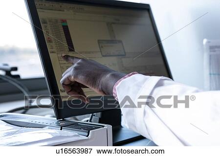 Stock Photo - Young female scientist pointing at computer screen in laboratory, cropped. Fotosearch