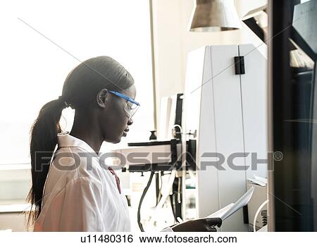 Young female scientist reading notebook in laboratory View Large Photo Image Stock Photograph - Young female scientist reading notebook in laboratory. Fotosearch