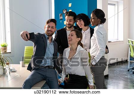 Young male and female business creative team taking smartphone selfie in open plan office View Large Photo Image Stock Image - Young male and female business creative team taking smartphone selfie in open plan office. Fotosearch
