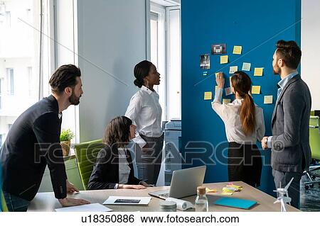 Young male and female business creative team brainstorming with sticky notes in office View Large Photo Image Stock Photograph - Young male and female business creative team brainstorming with sticky notes in office. Fotosearch